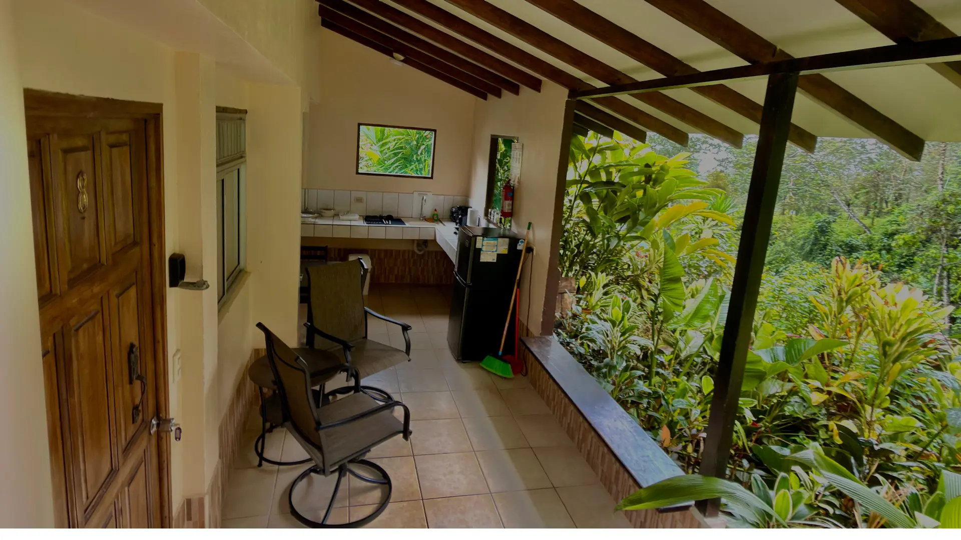 Terraza privada con sillas de descanso, área de cocina equipada y vista al bosque en Loma Real Hotel.