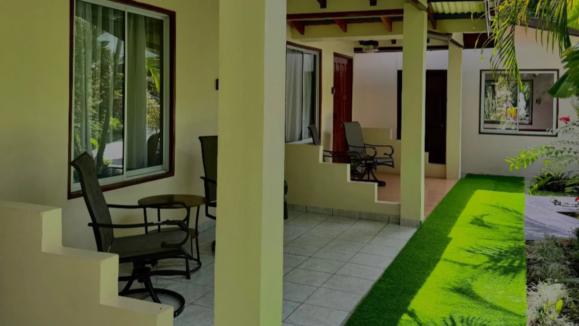 Pasillo exterior y terrazas privadas de las villas con sillas de descanso y jardines tropicales en Loma Real Hotel & Hot Springs.