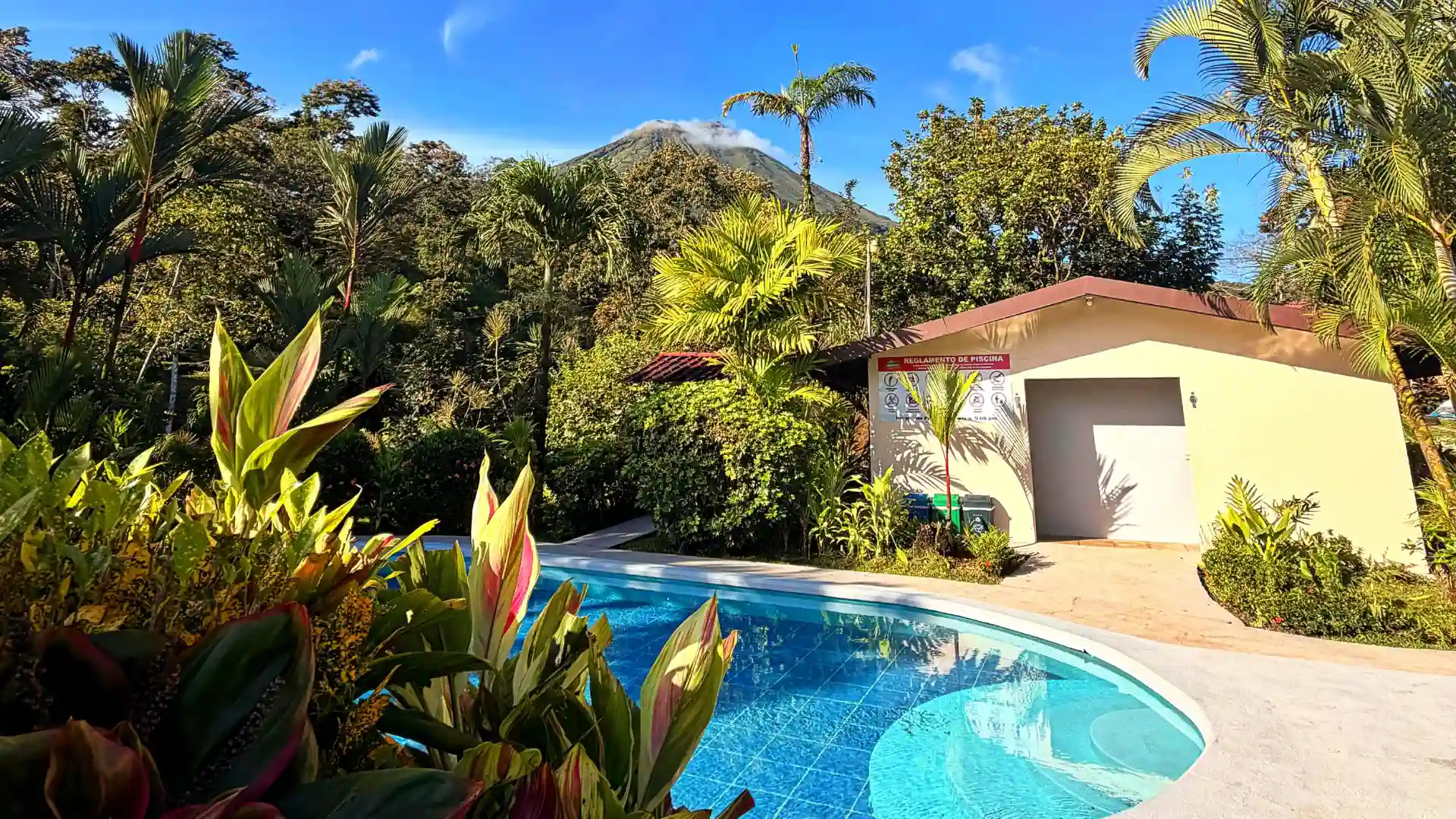 piscina al aire libre rodeada de vegetación tropical con vista directa al Volcán Arenal en Loma Real & Hot Springs, La Fortuna.