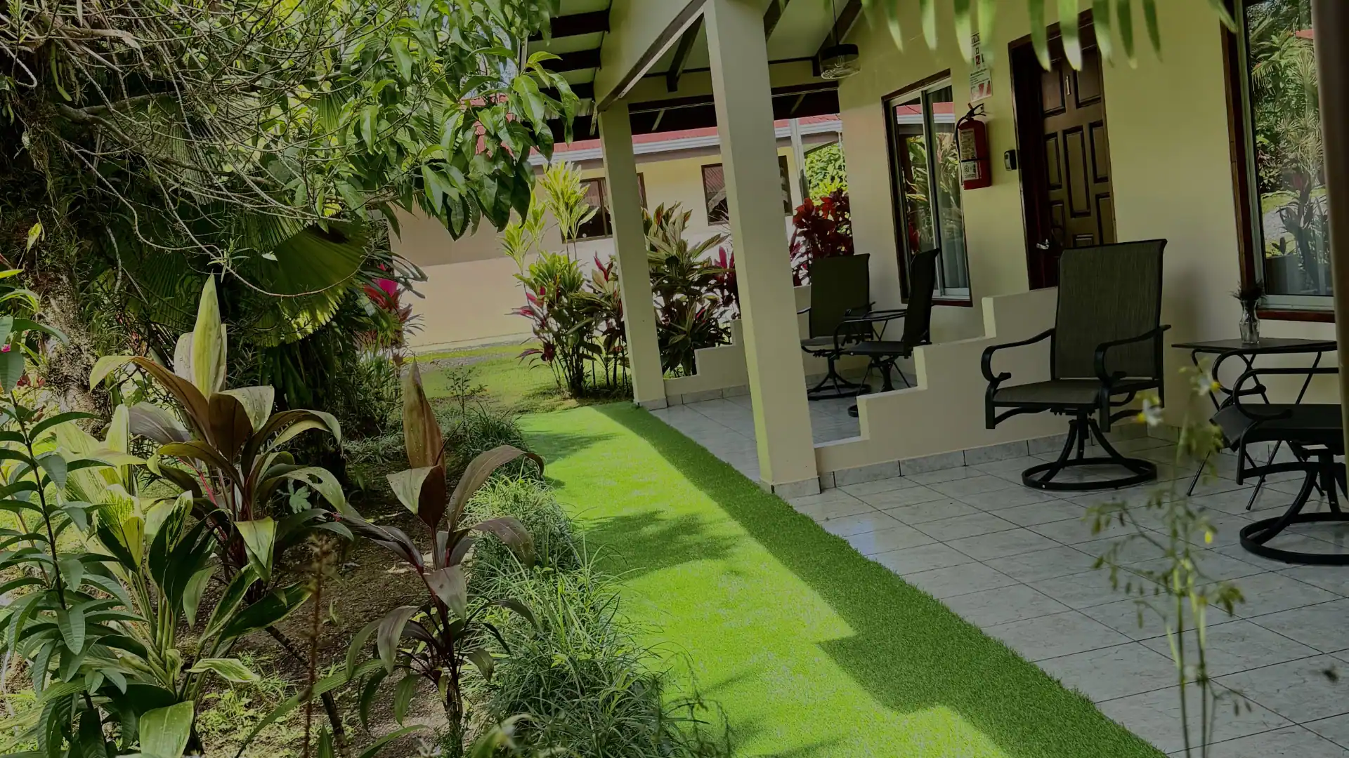 Pasillo exterior accesible en planta baja con sillas mecedoras frente a las habitaciones de Loma Real Hotel, diseñado para personas con movilidad reducida.